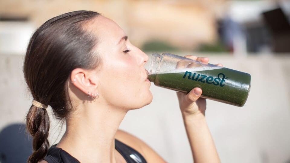 A person drinks Nuzest Good Green Vitality for a nutrient-rich superfood boost