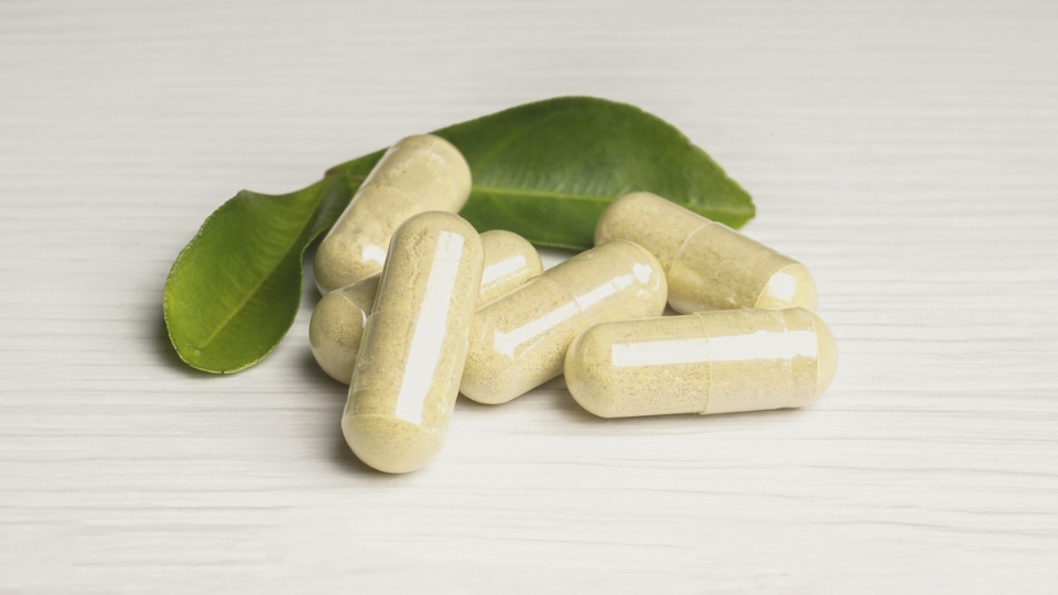Vitamin capsules with leaves behind them.