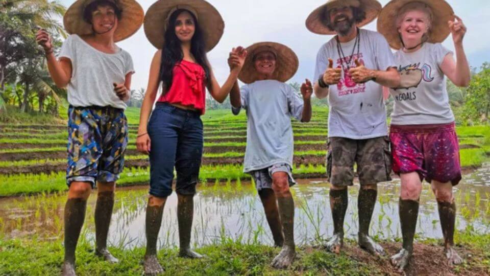 A group of people discovering the muddy rice fields at Balitrees Retreats.