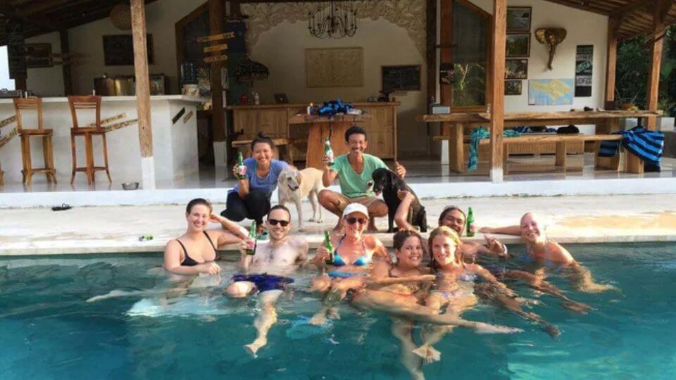 A happy group of people drinking beer in the pool at Pelan Pelan Surf Camp & Yoga Retreat in Bali.