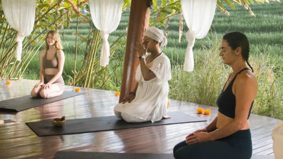 People kneel on their yoga mats during a session at a health retreat at De Moksha Eco-friendly Boutique Resort in Bali.