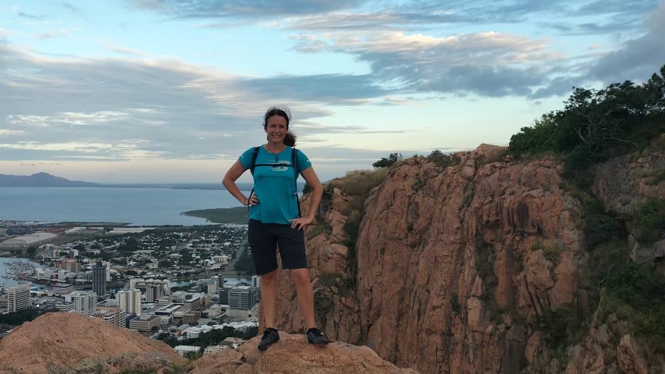 Elly stands smiling at the top of Castle Hill, a hiking trail in Townsville, while wearing the Mesa Trail barefoot trail shoes from Xero Shoes.