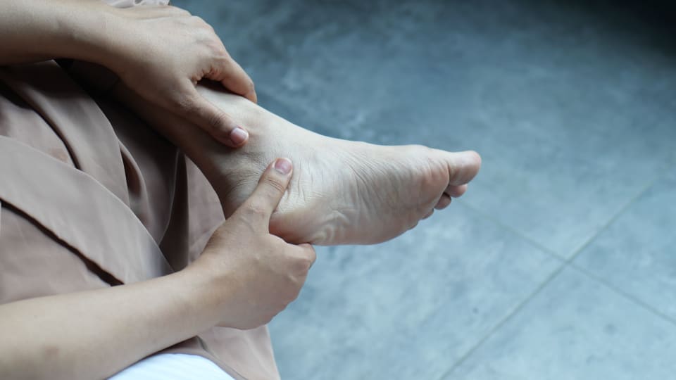 A person applies pressure with their thumb to the inside of their foot.
