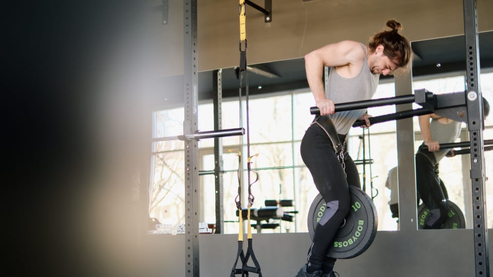 A person doing a weighted dip, one of the four core lifts of streetlifting.