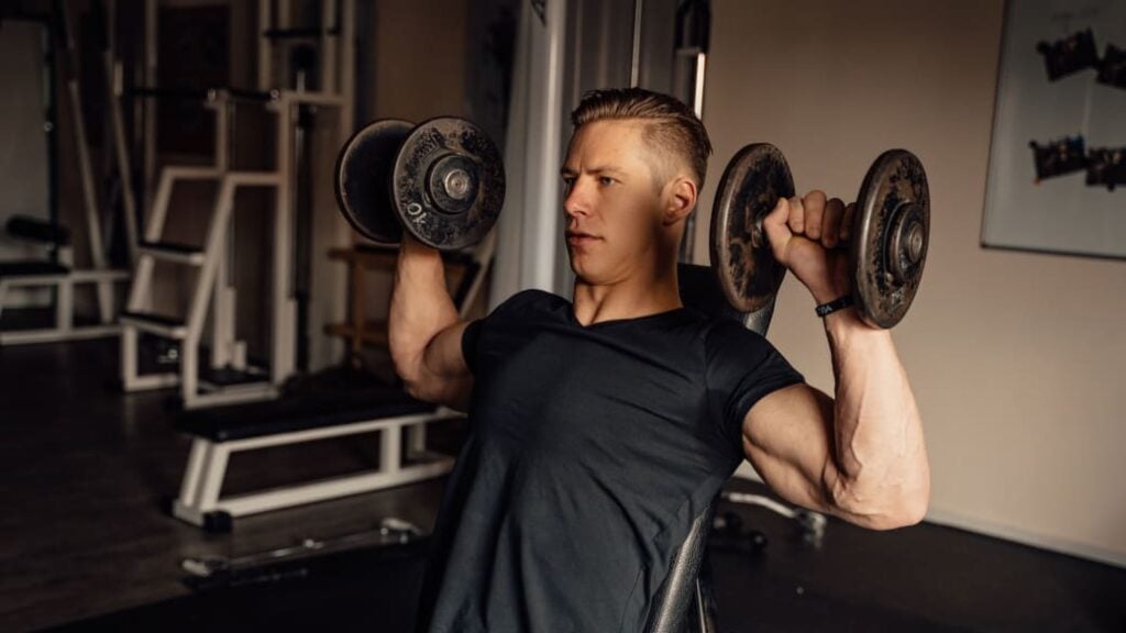 A person doing a seated dumbbell press, a compound exercise targeting the shoulders and triceps.