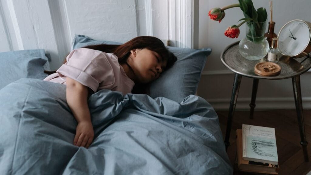 A person lies on their side asleep in bed.